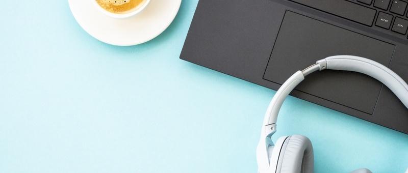 Headphones, laptop and coffee against blue background.