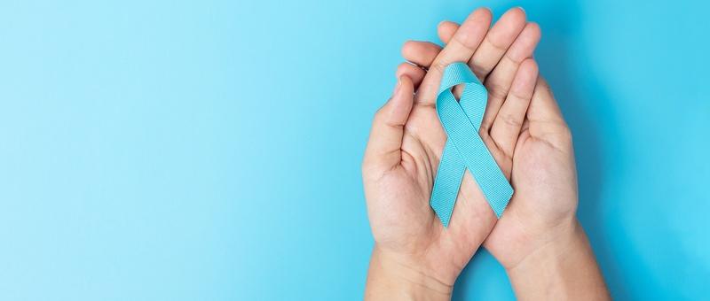Male hands holding Diabetes Awareness ribbon against a blue background.