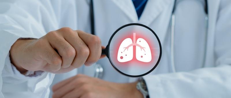 Healthcare professional in white coat holding magnifying glass showing glowing red lung illustration