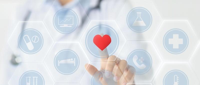 Hand touching digital healthcare interface with red heart icon surrounded by medical symbols in hexagonal buttons.