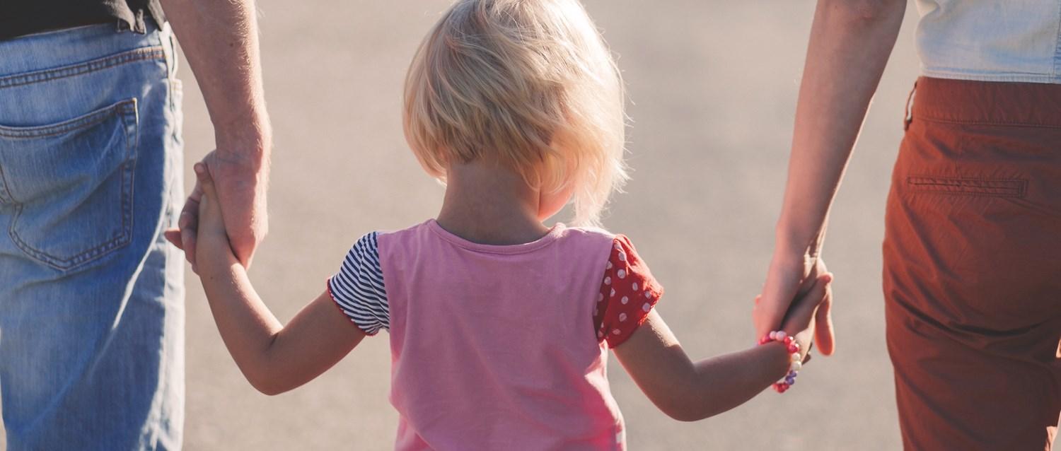 Child holding hands with parents