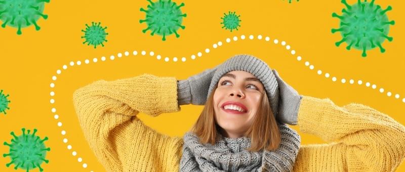 Blonde haired woman wearing grey winter scarf, hat and yellow jumper surrounded by green, virus-themed graphics against a yellow background, with dotted line around herself.