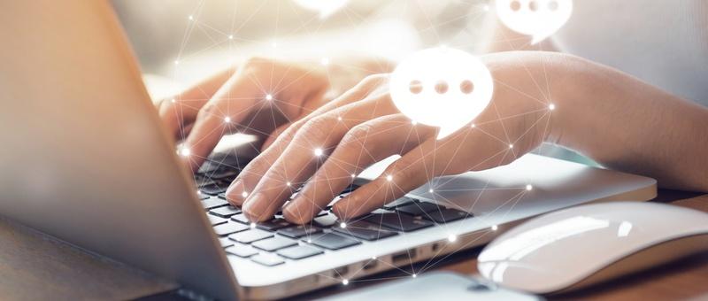 Hands typing on laptop keyboard with digital chat bubbles and network connection points overlaid, suggesting online communication.